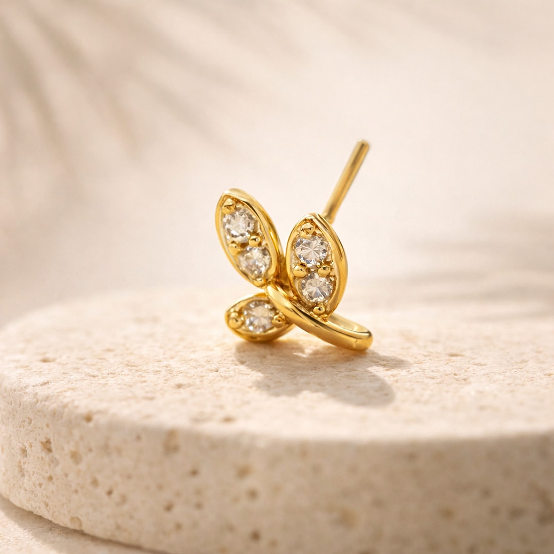 Stud de nez papillon serti de zircons ronds, tige fine, posé sur une pierre claire