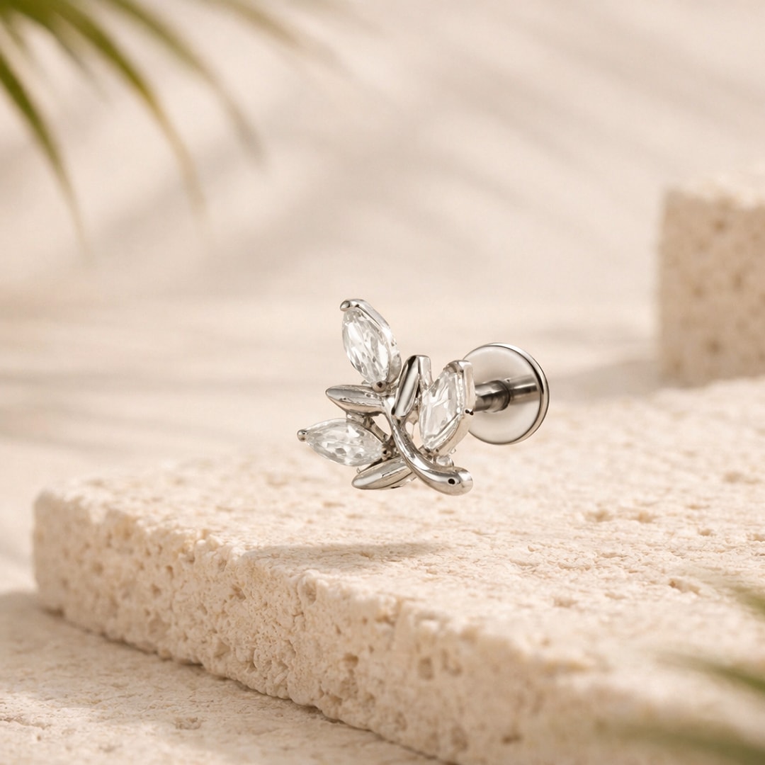 Stud flat back en titane argenté, motif feuille à trois zircons marquise, posé sur une pierre claire