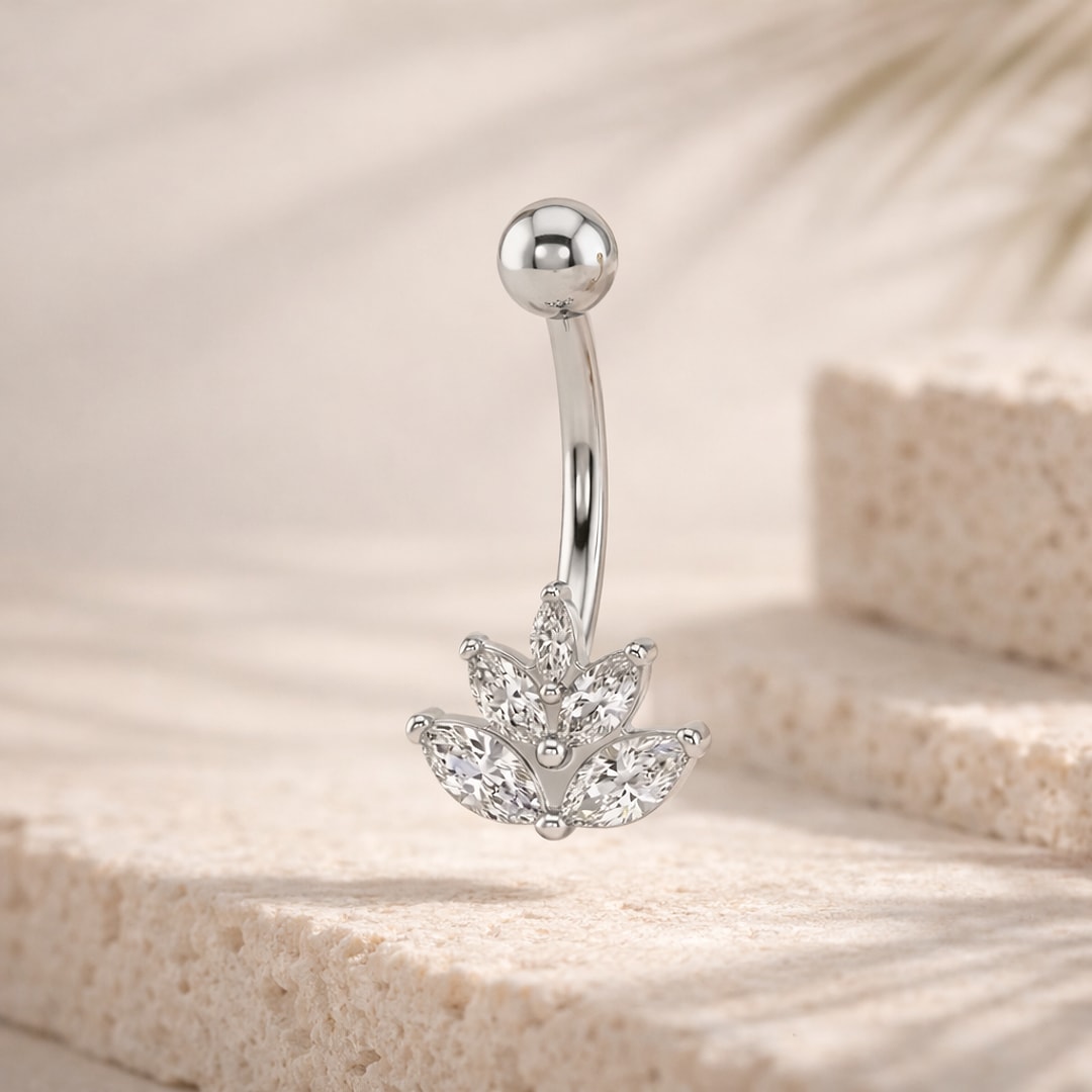 Piercing nombril acier argenté avec motif lotus en six pierres marquises et bille polie, posé sur pierre claire