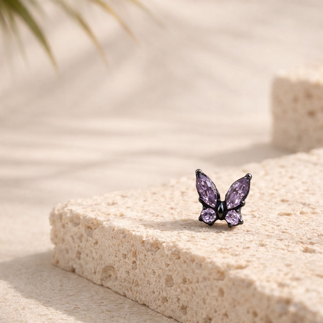 Nose stud papillon en titane noir serti de zircons violets posé sur une pierre claire