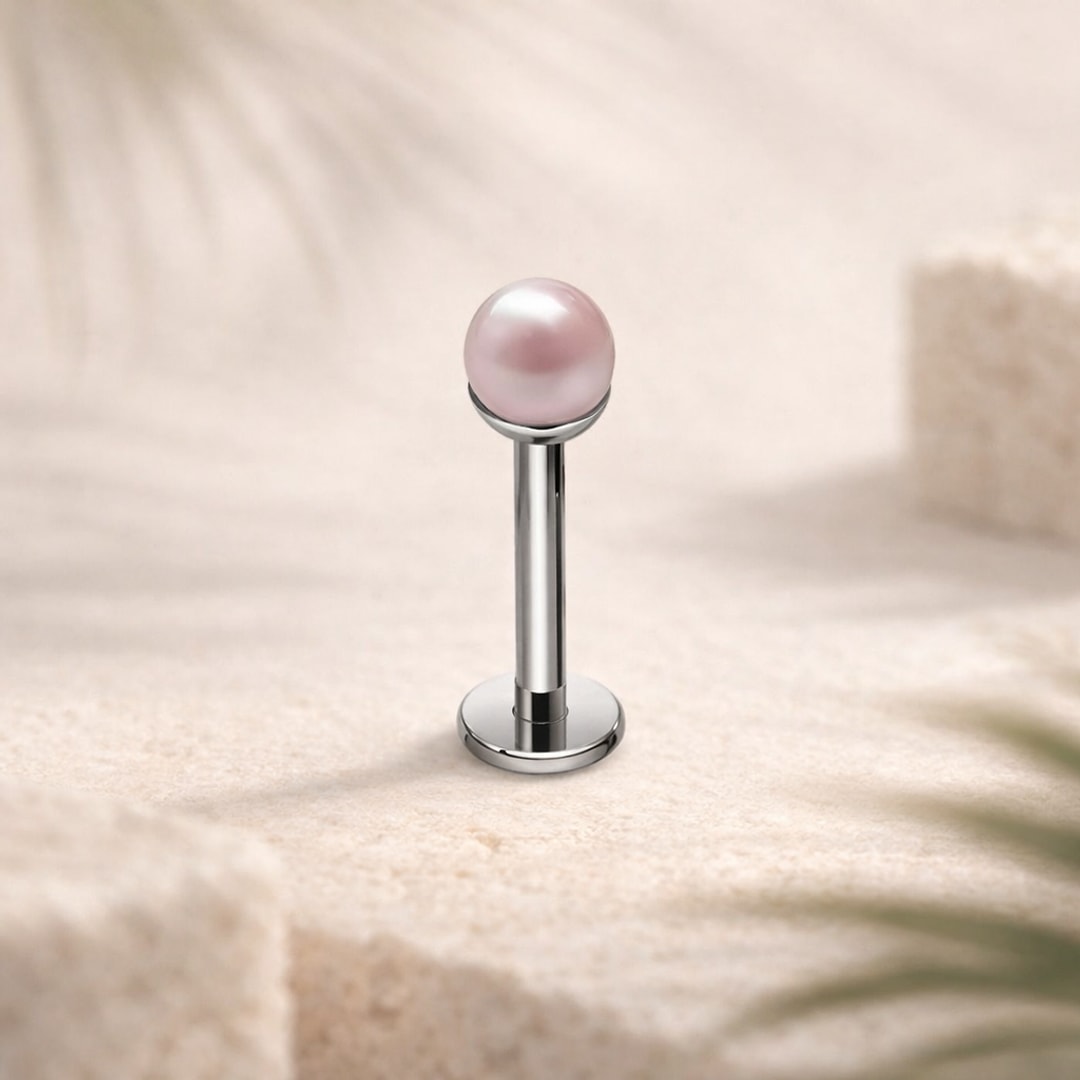 Labret flat back en titane argenté avec fausse perle rose de 4 mm, posé sur une pierre claire