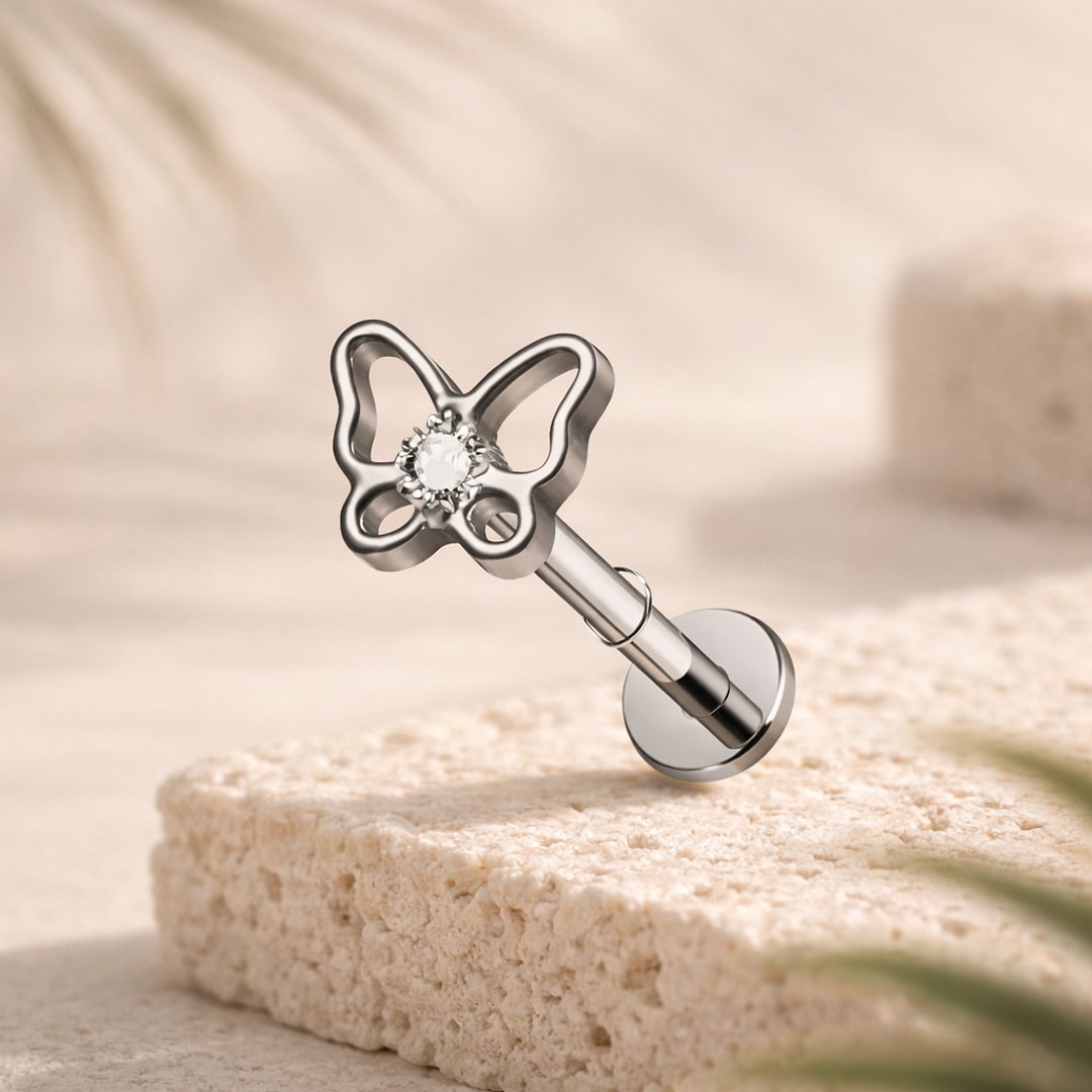 Stud flat back titane argenté papillon ajouré avec zircon central, tige 1,2 x 8 mm posée sur pierre claire