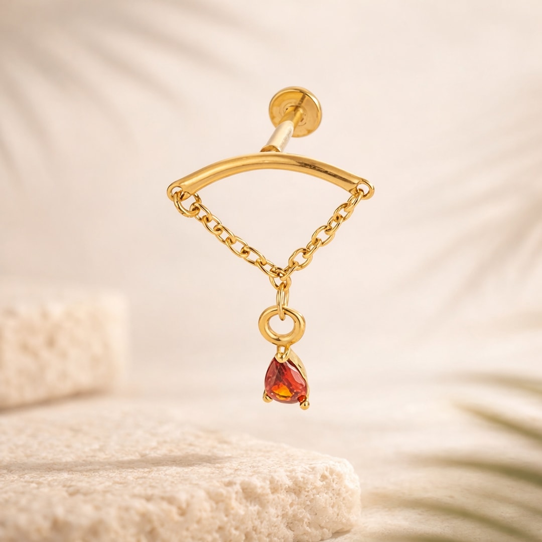 Labret doré à chaînette avec pendentif goutte en zircon rouge sur fond beige