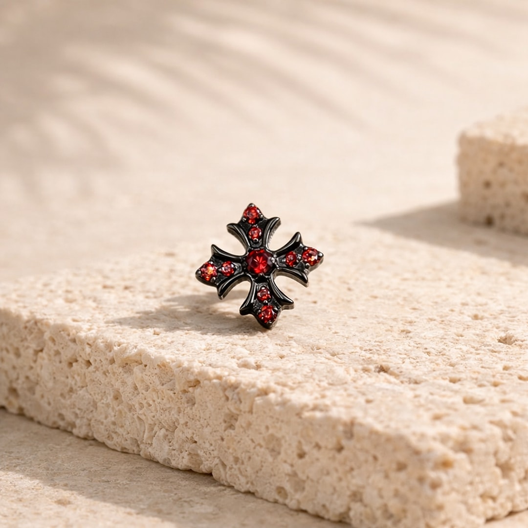 Stud flat back titane noir en forme de croix gothique sertie de zircons rouges, posé sur une pierre claire