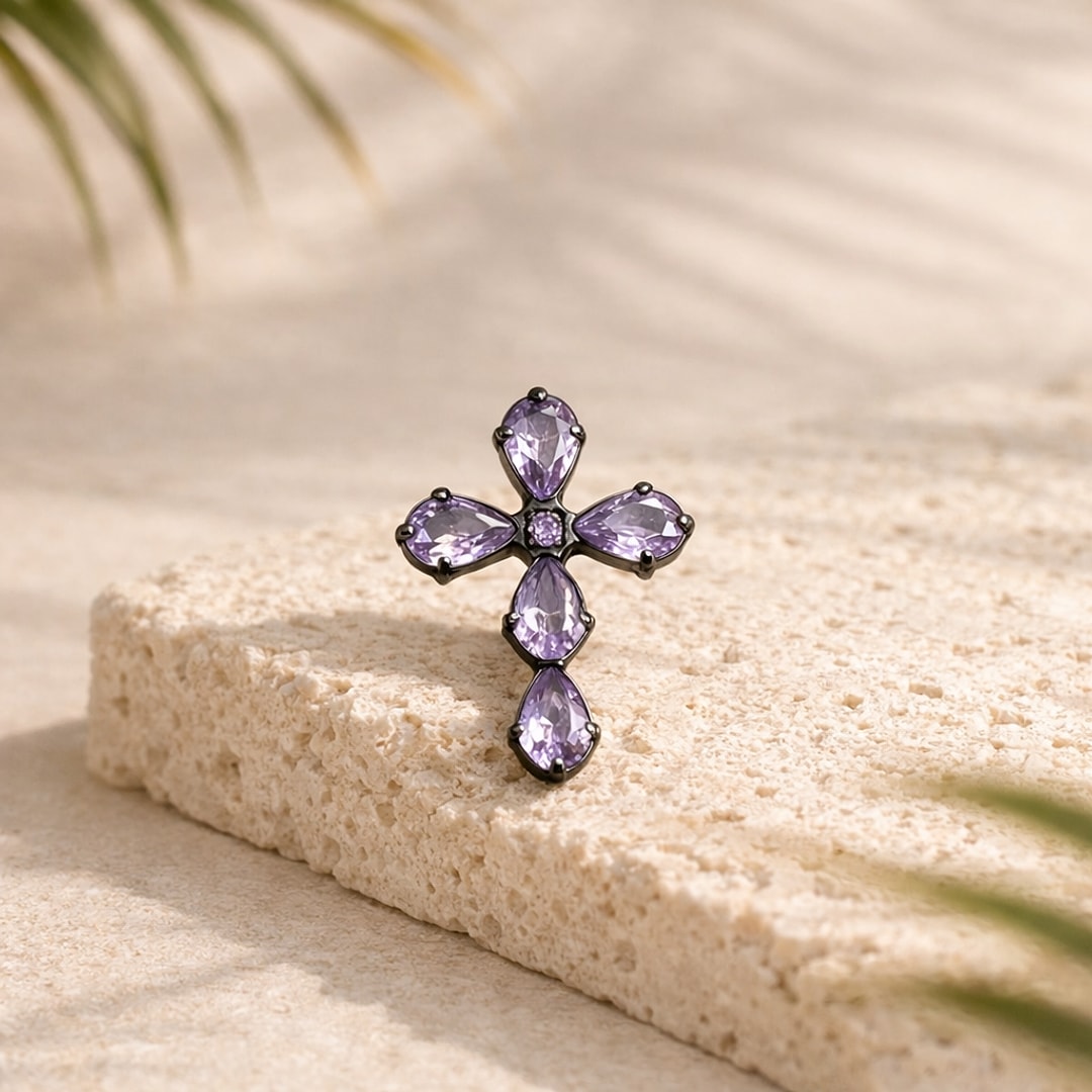 Stud flat back en titane noir en forme de croix sertie de zircons violets poire, posé sur une pierre claire