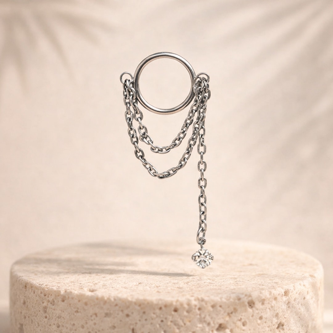 Anneau en titane argenté avec trois chaînes pendantes et petit zircon serti, sur socle en pierre claire