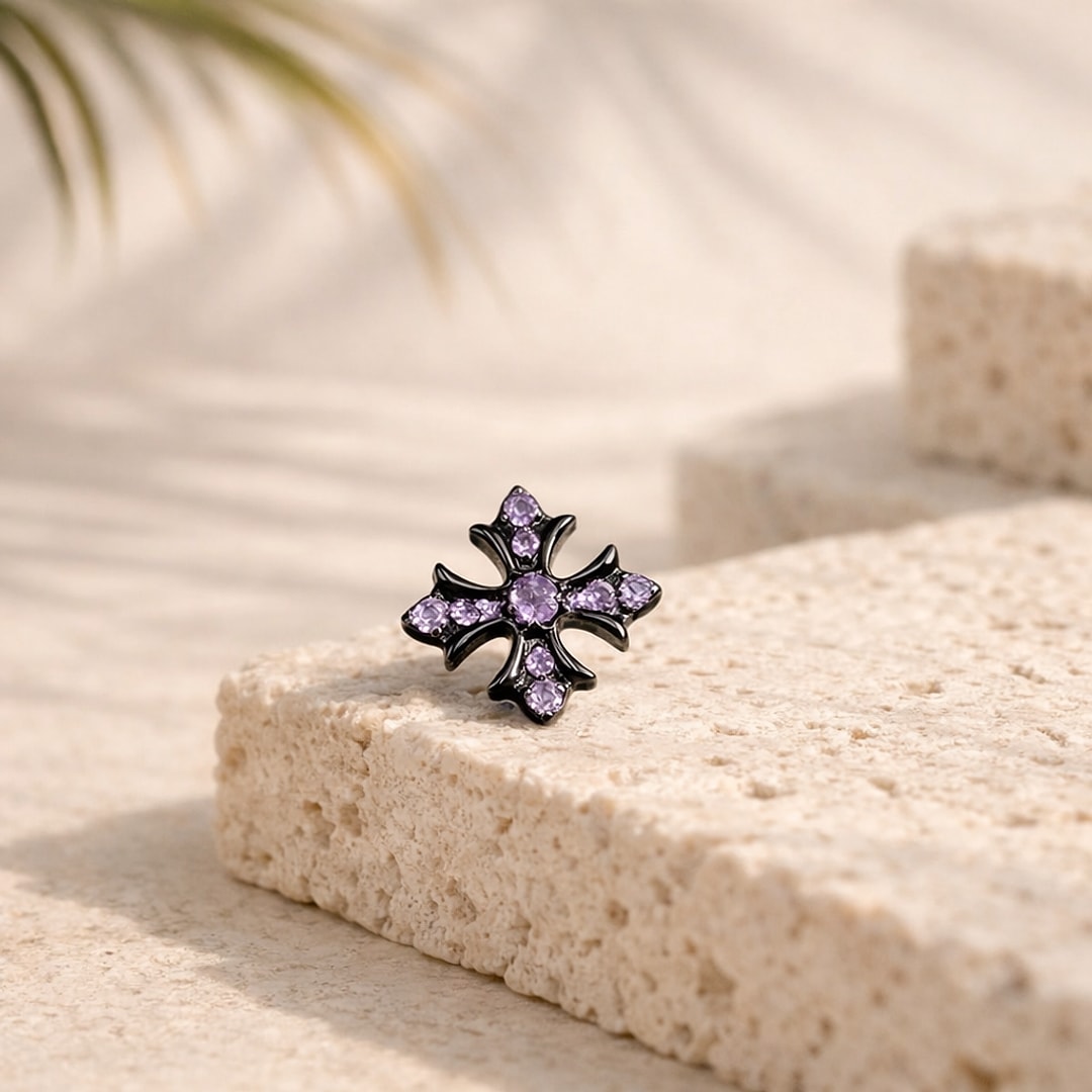 Stud flat back titane noir en forme de croix gothique sertie de zircons violets, posé sur une pierre claire