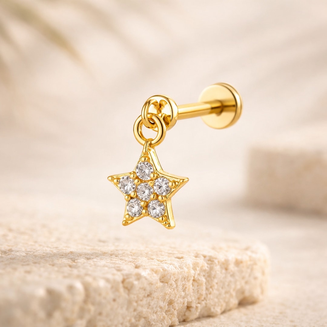 Stud flat back doré avec pendentif étoile serti de pierres blanches, posé sur une pierre claire