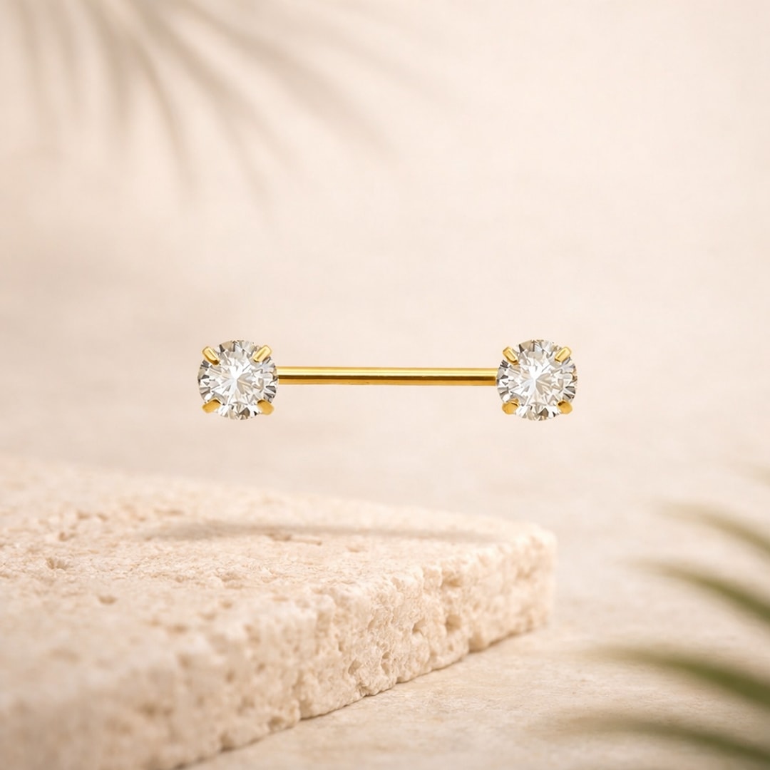 Barre de téton en titane doré avec un zircon rond serti griffes à chaque extrémité, sur fond beige