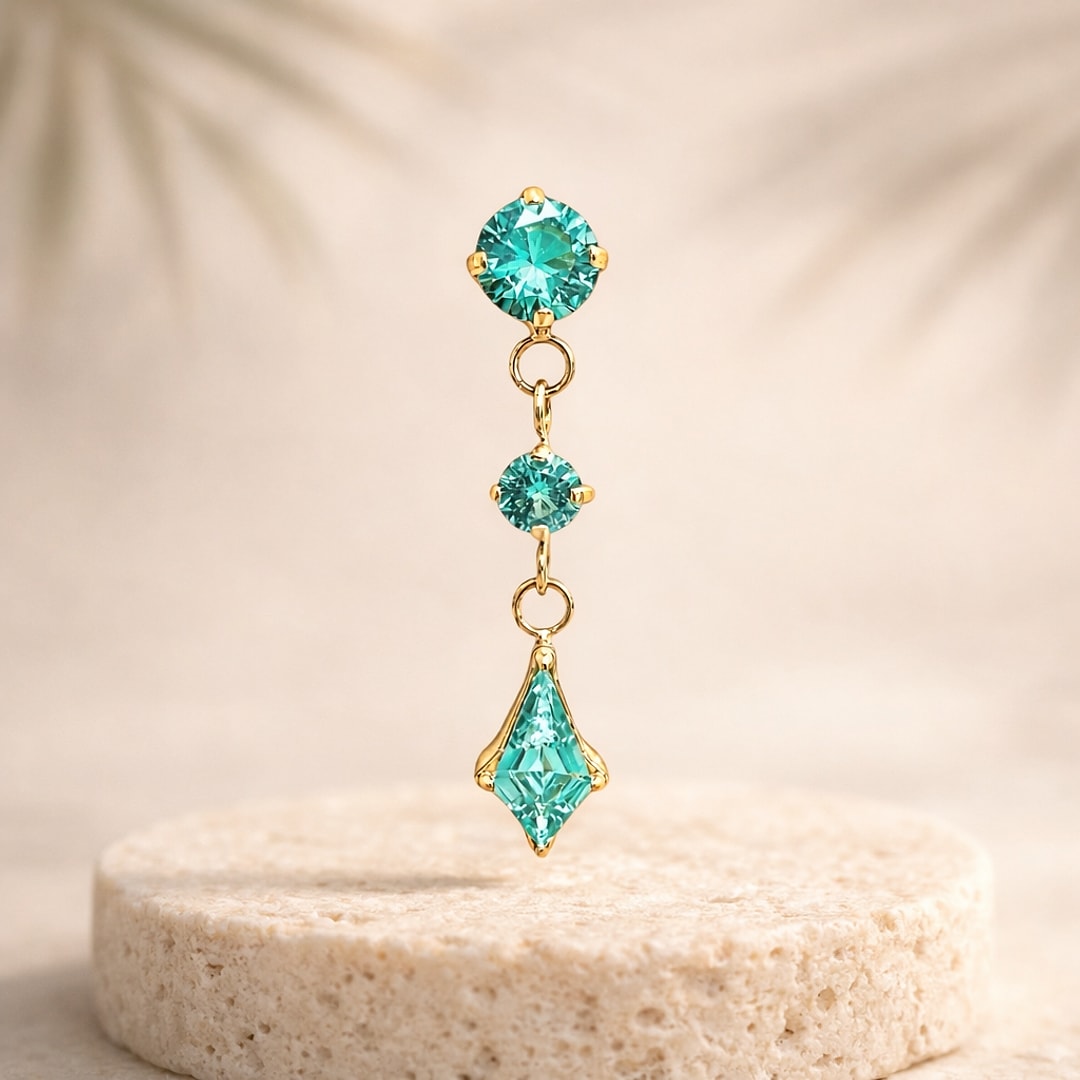 Top de labret en titane doré avec trois zircons turquoise pendants, dont un losange effilé, posé sur une pierre claire