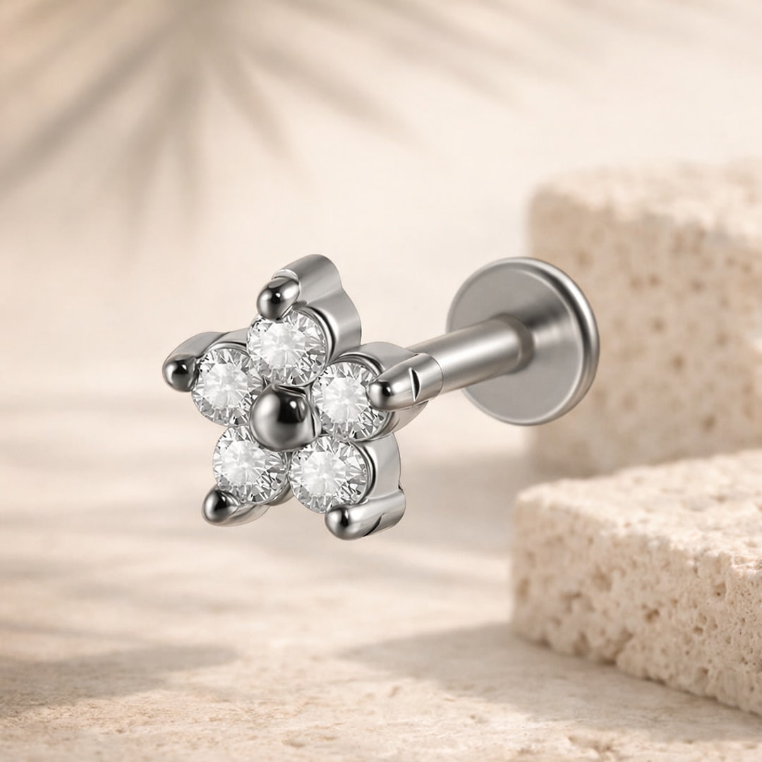 Labret acier argenté motif fleur à cinq cristaux blancs, tige à disque plat, posé sur pierre claire