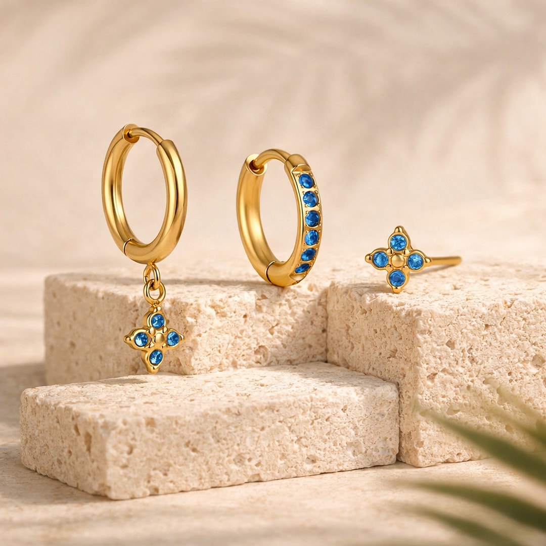 Lot de 3 bijoux d'oreille dorés : créole à fleur pendante, créole sertie de zircons bleus et puce fleur bleue