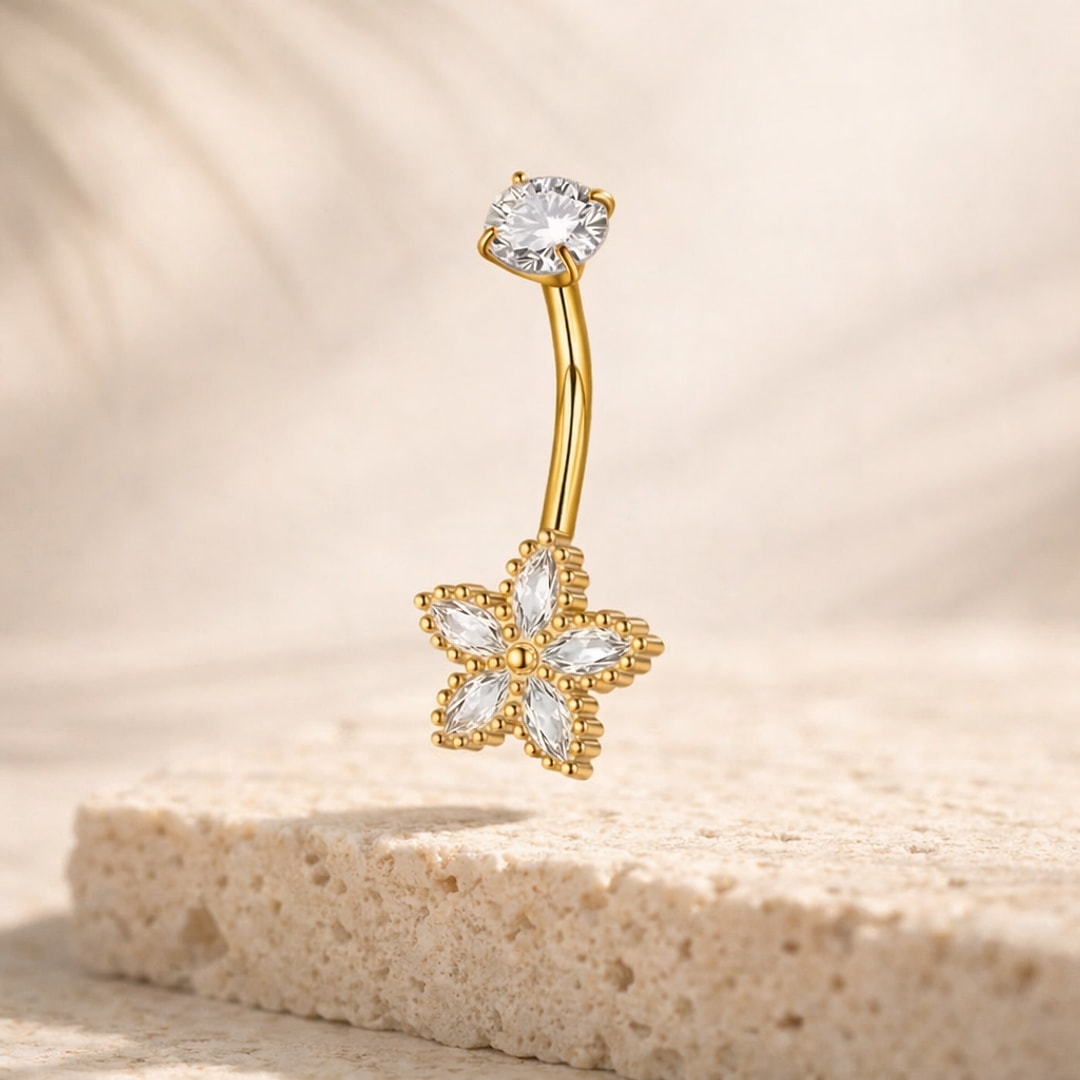 Piercing nombril doré avec fleur à cinq pétales en zircons blancs et pierre ronde sertie griffes, posé sur pierre claire