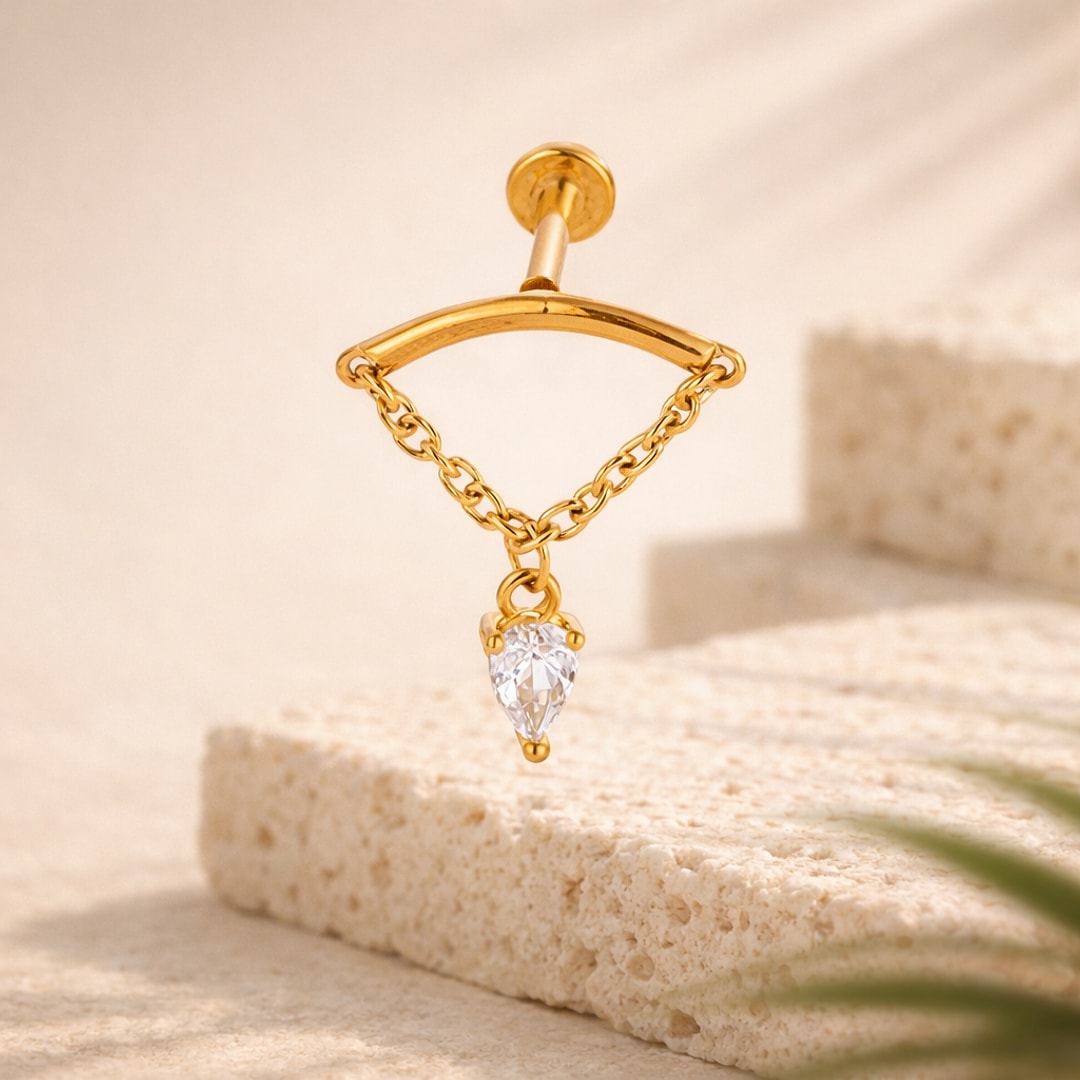 Labret doré avec chaînette fine et pendant zircon blanc en forme de goutte, posé sur pierre claire