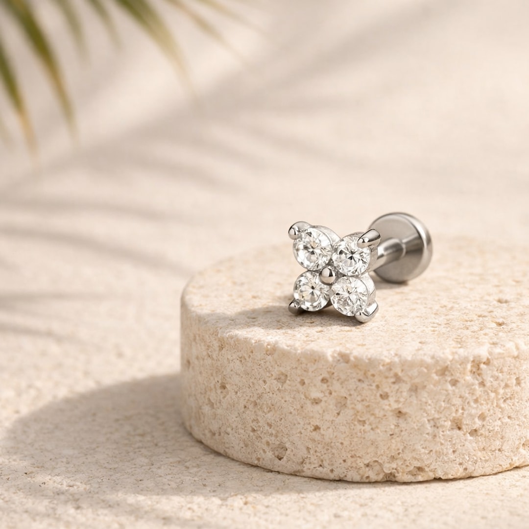 Labret acier argenté à motif fleur de quatre zircons blancs, posé sur une pierre claire
