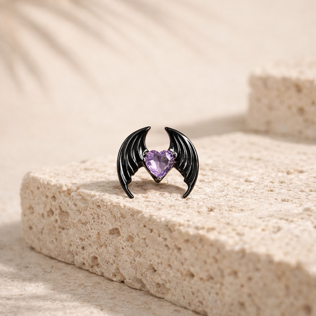 Stud de nez en titane noir en forme d'ailes de chauve-souris avec un cœur en zircon violet, posé sur une pierre claire