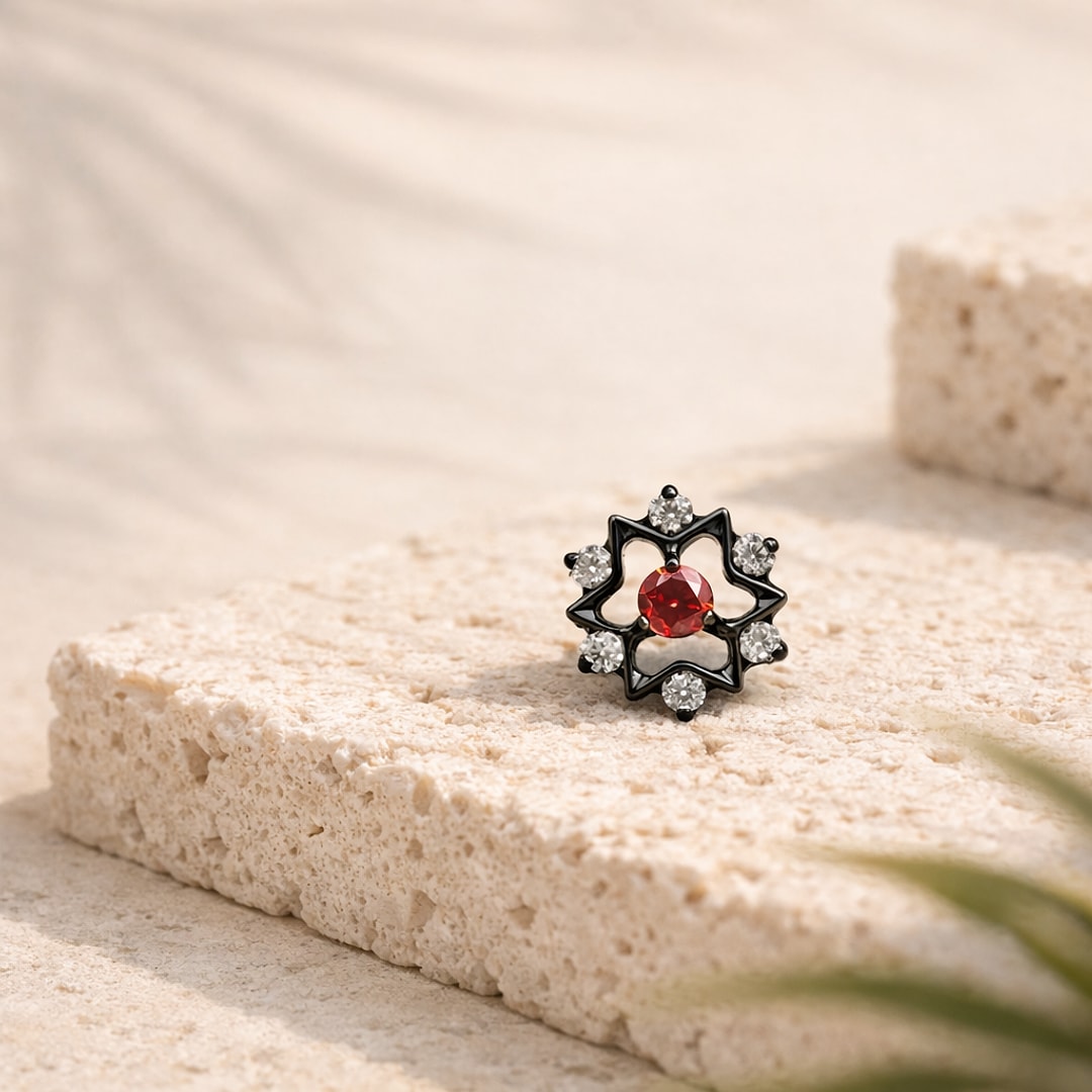 Stud flat back titane noir en forme d'étoile, zircon rouge central et six zircons blancs, posé sur pierre claire