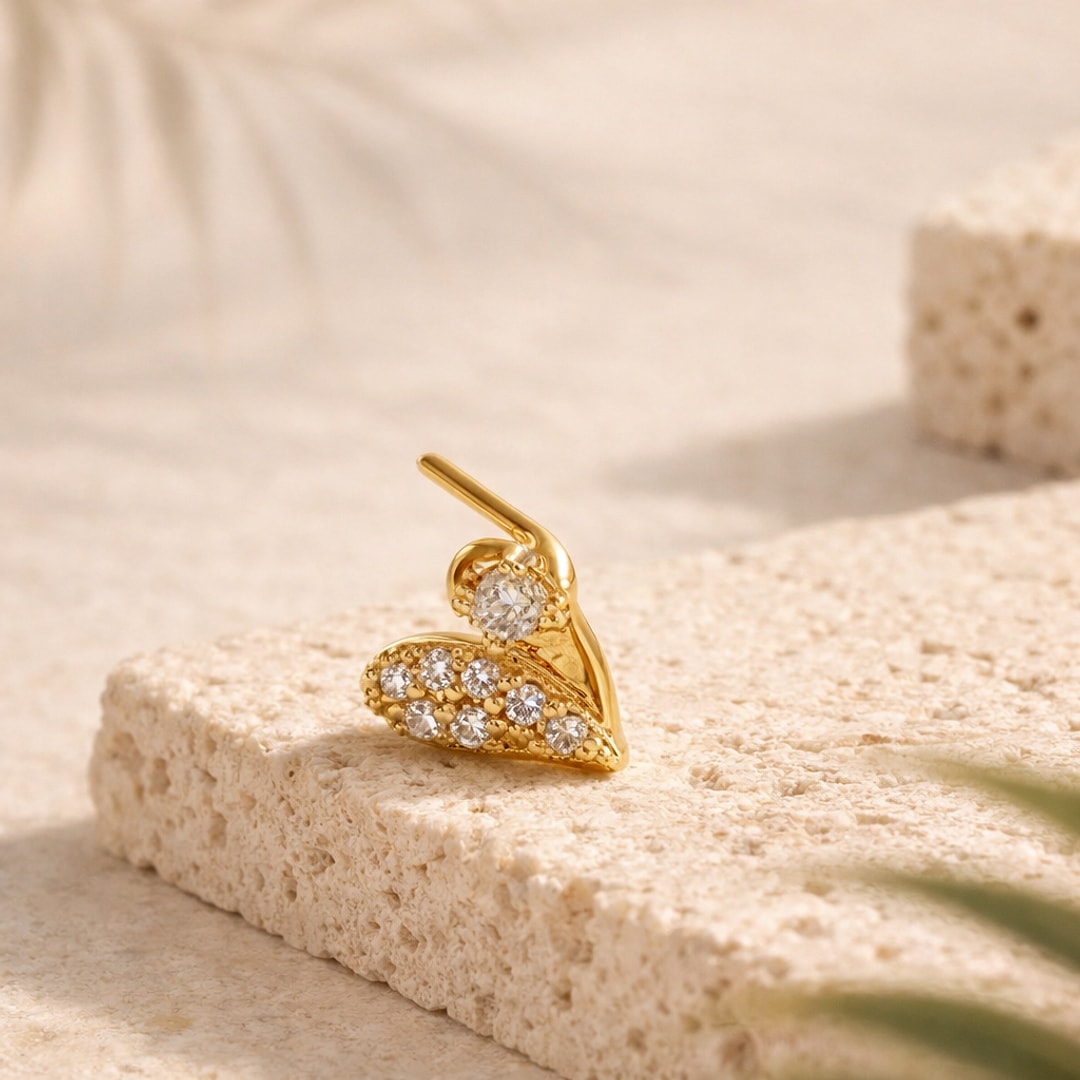 Nose stud doré en forme de cœur pavé de zircons blancs, tige coudée en L, posé sur pierre claire