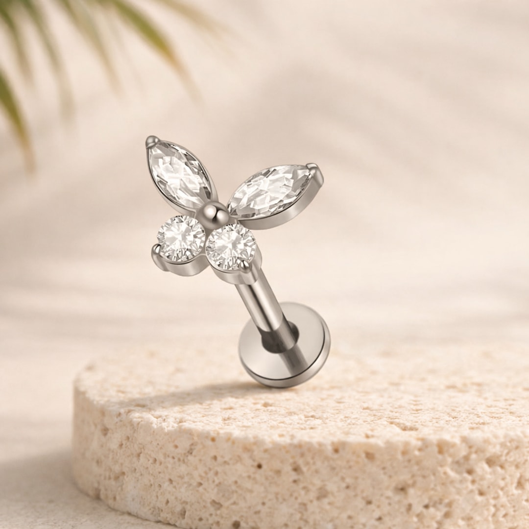 Labret acier argenté à motif papillon, deux cristaux marquise et deux pierres rondes, posé sur une pierre claire