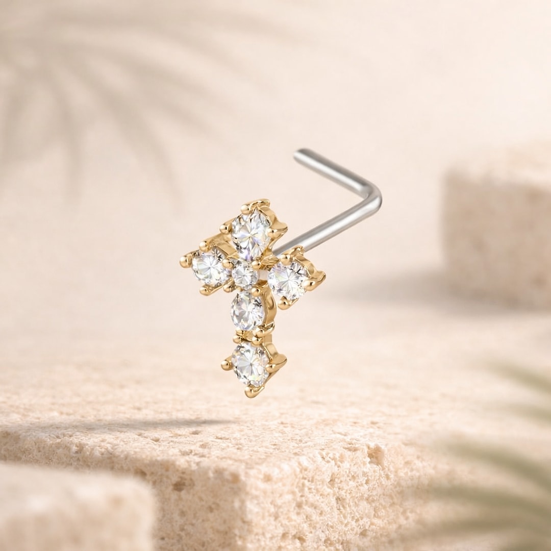 Stud de nez en L à tige acier, motif croix doré serti de six zircons blancs, posé sur pierre claire