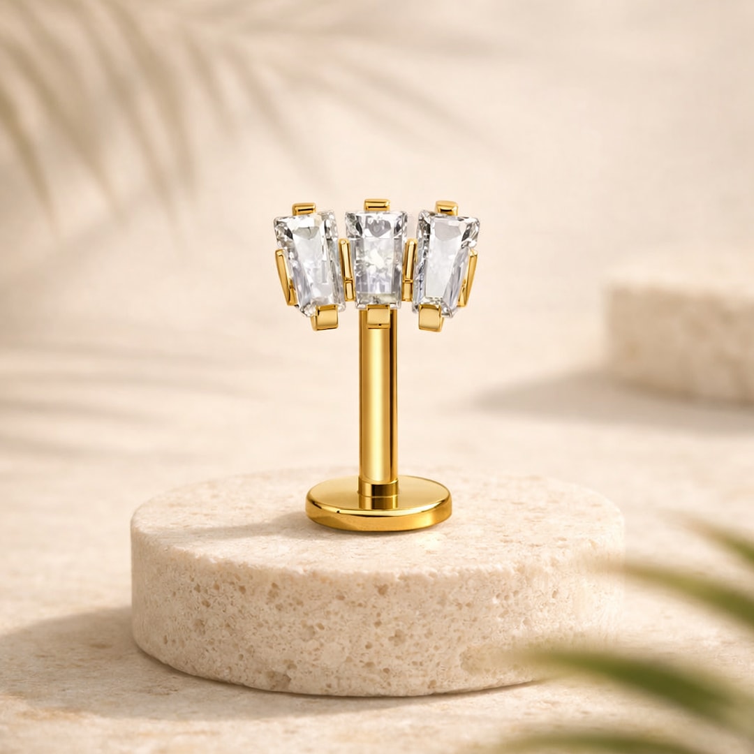 Labret flat back en titane doré orné de trois zircons blancs taille baguette, posé sur une pierre claire