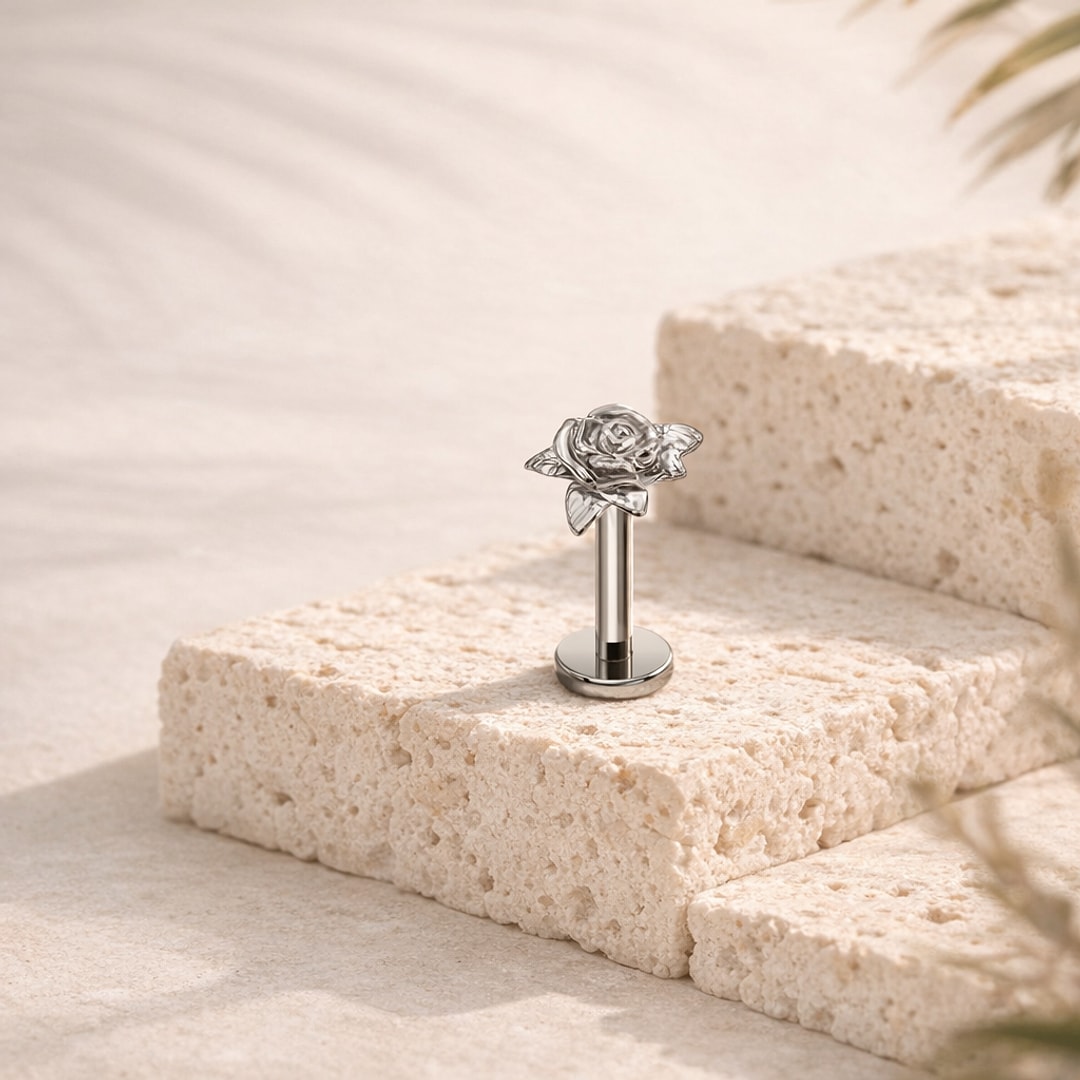 Stud flat back titane argenté avec motif de rose en relief, tige droite posée sur une pierre claire