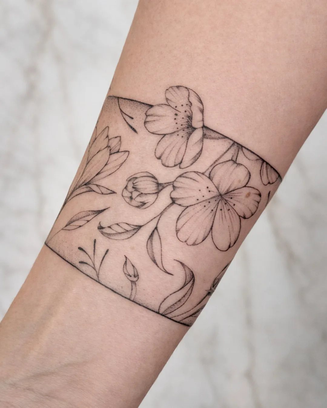 Tatouage femme bracelet de fleurs encadré sur le bras