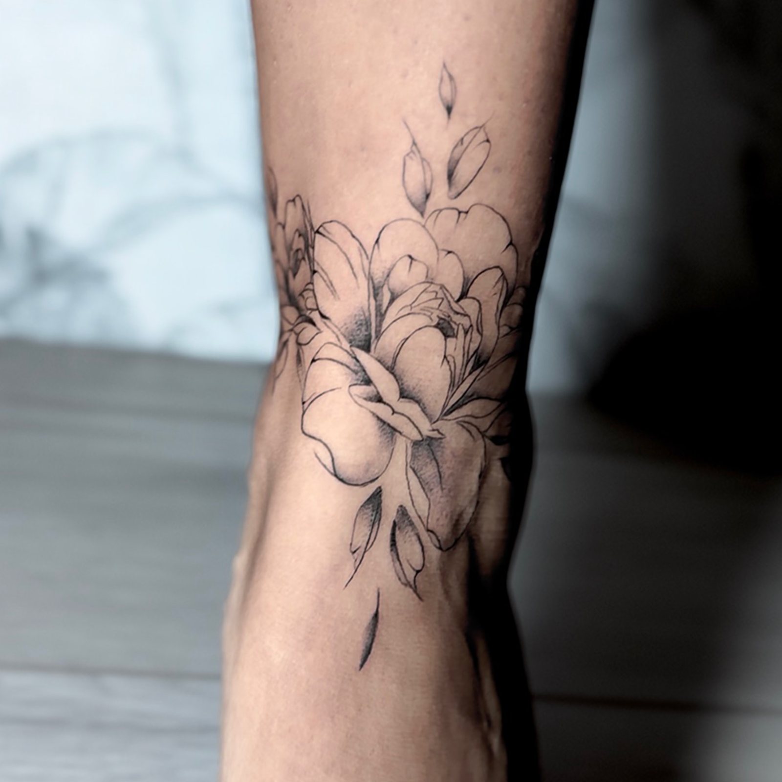 Tatouage femme fleurs en fine line autour de la cheville