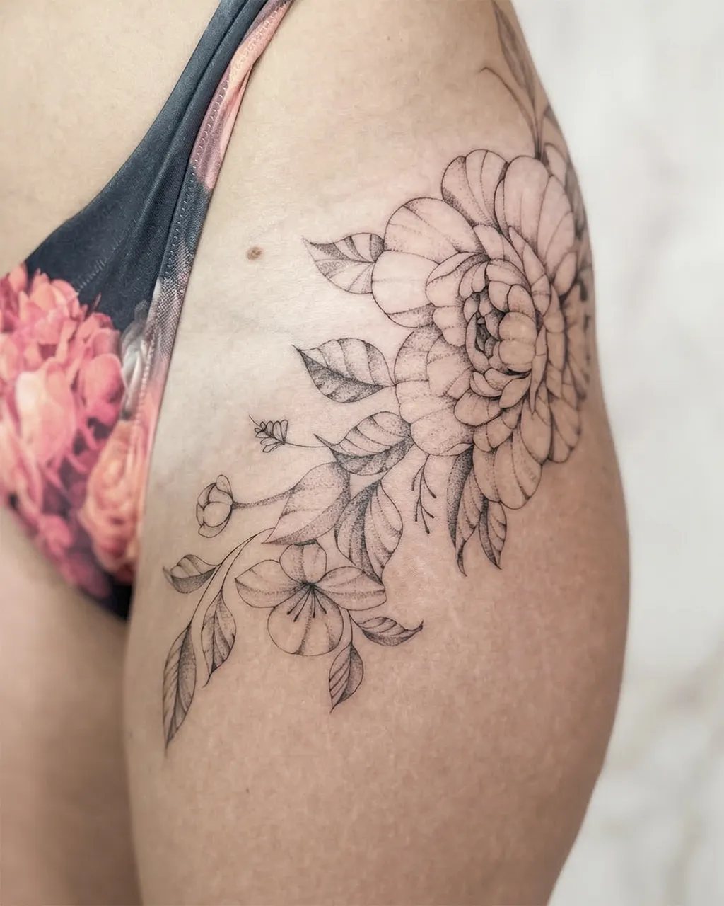 Tatouage pivoines et fleurs en fine line sur la hanche