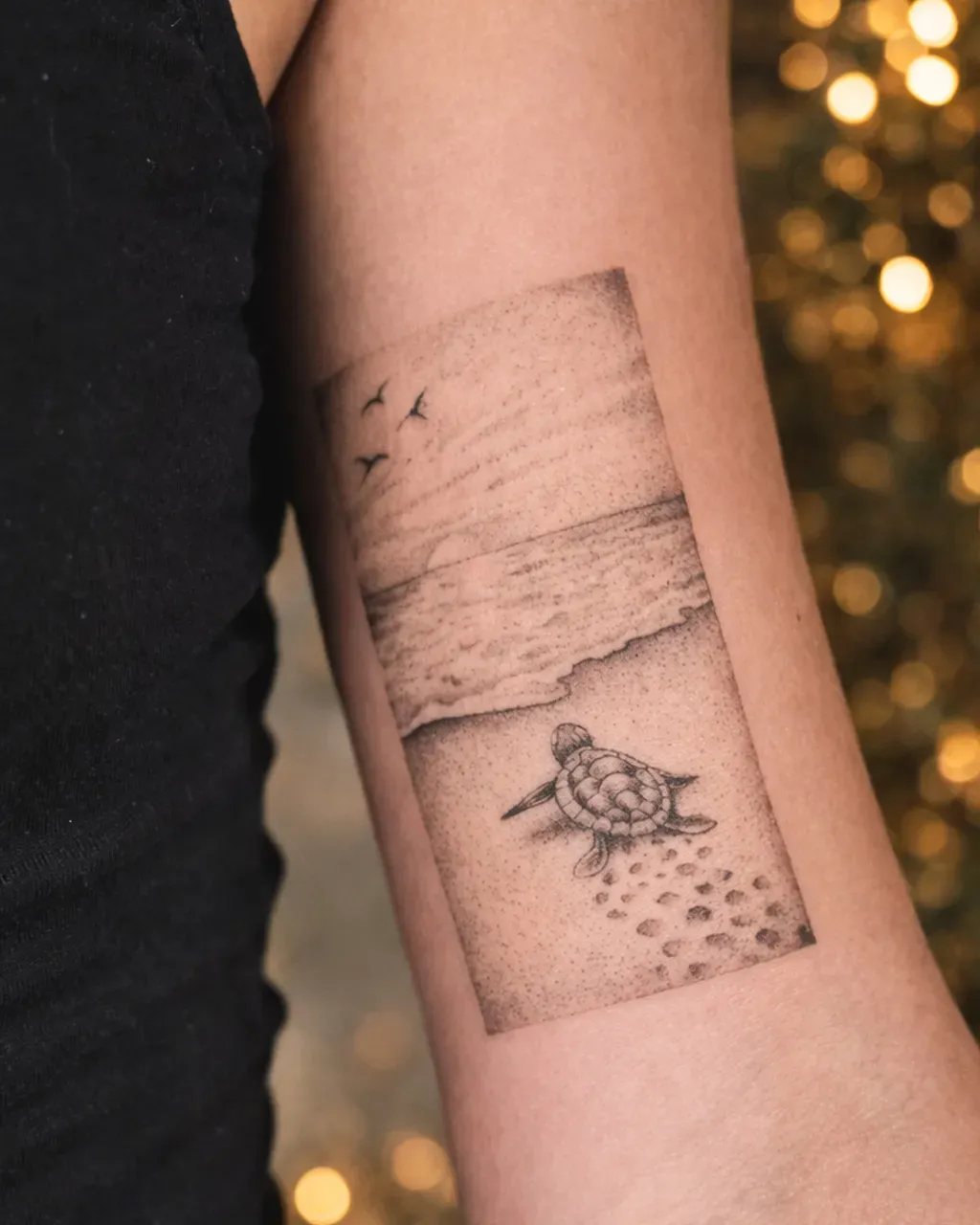 Tatouage fine line d’une bébé tortue rejoignant la mer sur la plage