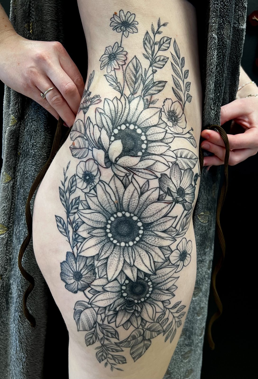 Grand tatouage floral de tournesols et fleurs sur la cuisse et la hanche, réalisé par Noon Tattoo Therapy à Saint-Denis
