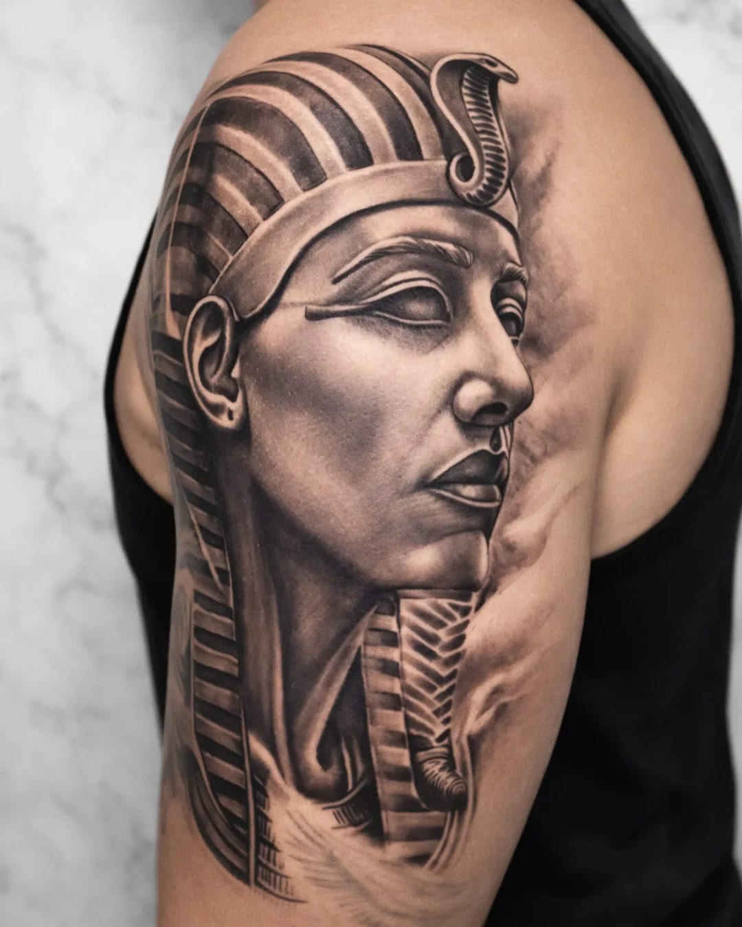 Tatouage homme pharaon réaliste en black and grey sur l’épaule et le haut du bras, réalisé par David à Saint-Louis, La Réunion