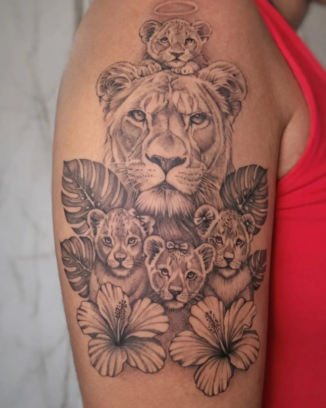 Tatouage lionne et ses lionceaux avec des hibiscus sur le bras
