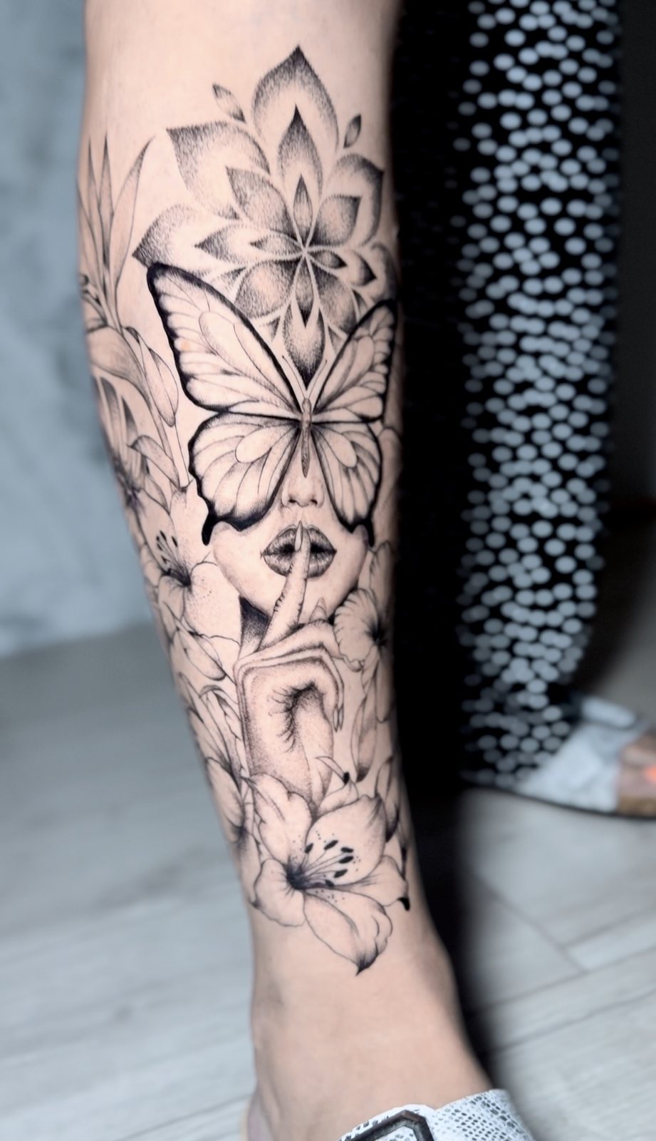 Tatouage papillon, mandala et fleurs sur la jambe
