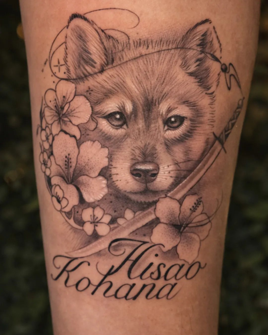 Tatouage réaliste d’un chien avec des fleurs et deux prénoms