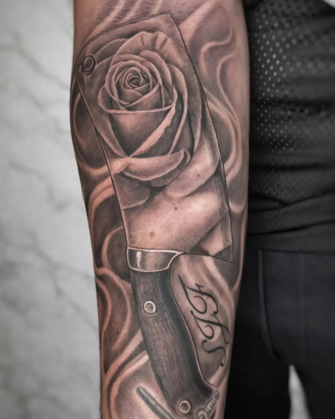 Tatouage rose et couteau réalistes sur l’avant-bras