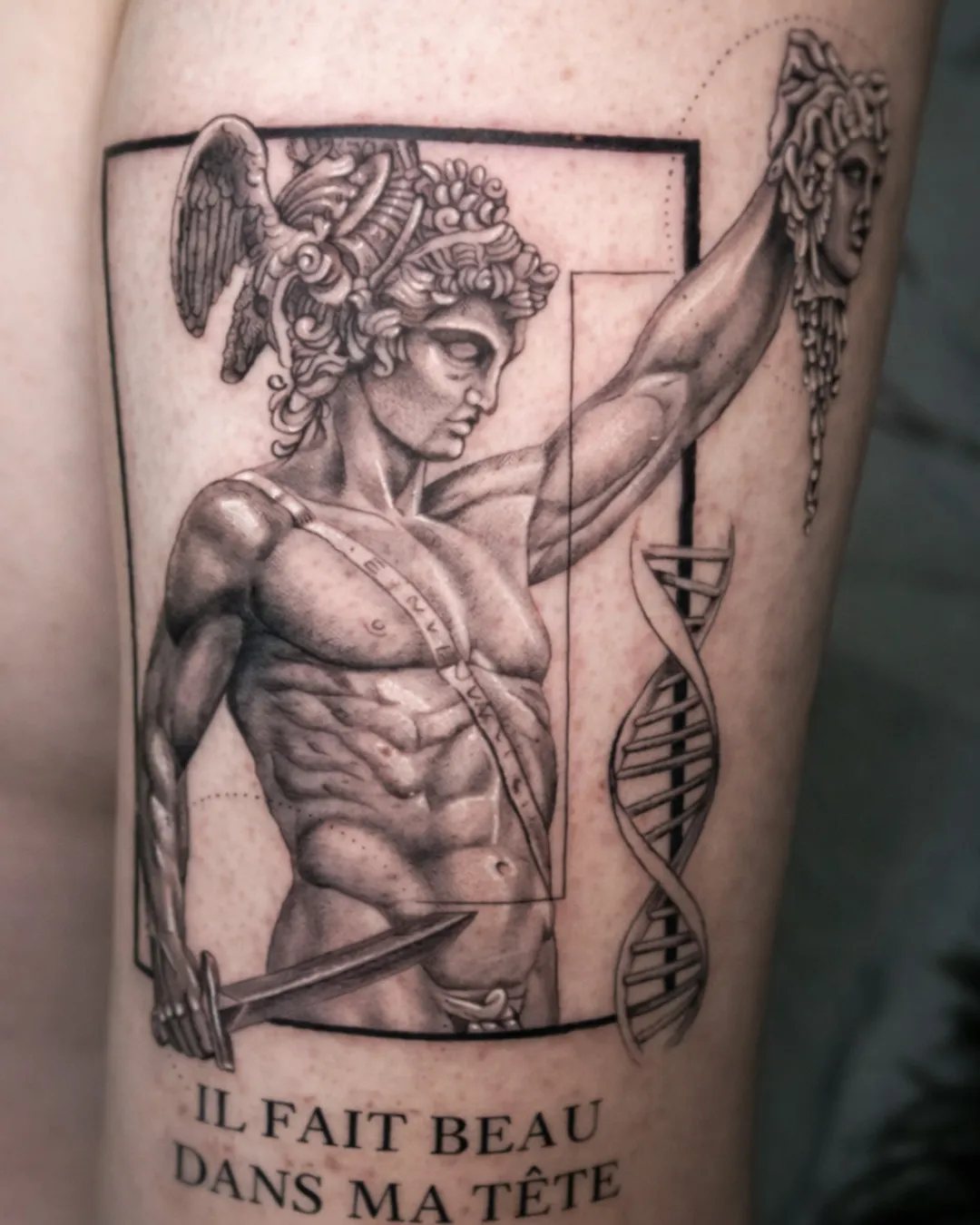 Tatouage statue antique réaliste avec la phrase « Il fait beau dans ma tête » sur le bras